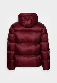 Chaqueta acolchada burdeos con capucha, que presenta un diseño acolchado, textura suave y puños elásticos. Sin hardware ni logotipos visibles.