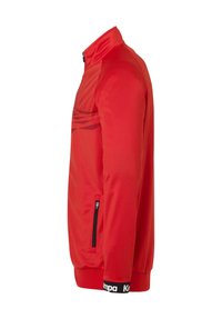 Rød atletisk jakke med opretstående krave, sidelommer med lynlås, tekstureret stof på den øverste brystdel og et sort bånd med logo ved kanten.