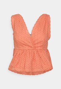 Blusa de cor pêssego com um decote em V profundo e bordas onduladas. Apresenta uma textura de ilhós e uma cintura franzida, criando uma silhueta esvoaçante.