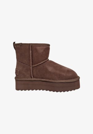 Stivaletto in camoscio marrone con punta arrotondata, suola spessa con plateau e dettagli cuciti. Presenta un tirante sul retro per un facile inserimento.