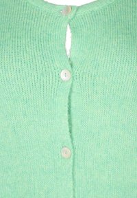 Světle zelený pletený kardigan s detaily ve tvaru klíčové dírky na zádech a bílými kulatými knoflíky vpředu. Jemná textura.