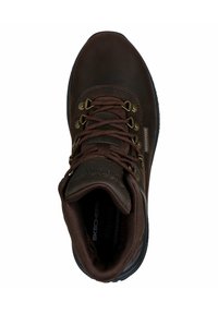 Bruine waterproof wandelschoen met bruine veters, metalen oogjes, een gevoerde kraag en een getextureerde rubberen zool, met ‘Skechers’ branding aan de zijkant.