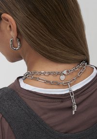 Sølv metal kæden halskæde med ovale led, med en lille charm og en lås detalje, båret om halsen med en ekstra hoops ørering.