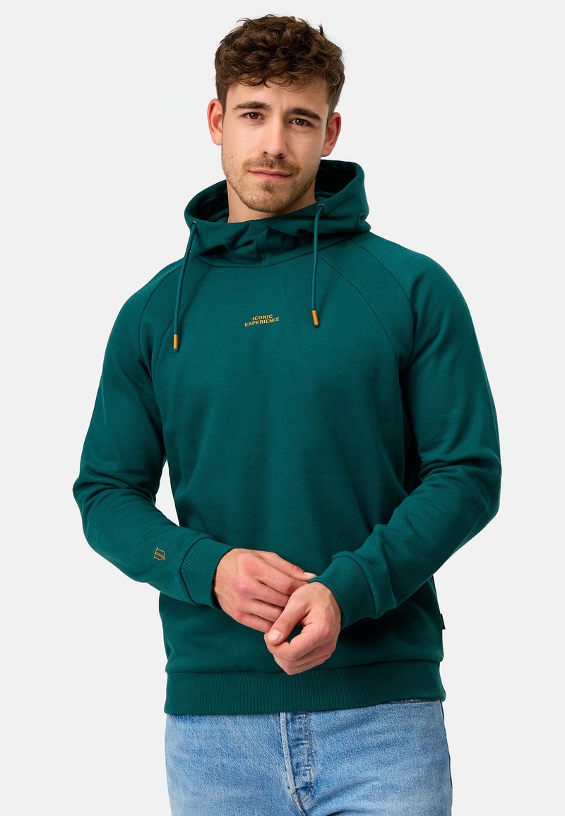 Teal huppari pehmeästä materiaalista, jossa on kengurupocket, kultaiset kirjaimet ja koristeelliset nyörit.