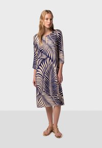 Navy and cream dress with 3/4 sleeves and palm leaf pattern; features a keyhole neckline and falls just below the knee.