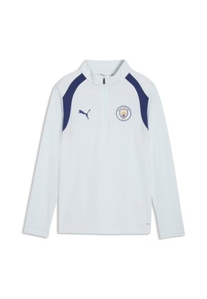 Biały sportowy top z długim rękawem z granatowymi paskami na ramionach, logo Manchester City na piersi, logo Puma i półzamkiem z przodu kołnierza.