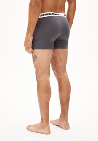 Graue Boxershorts aus weichem Material, mit einem weißen Gummibund mit dem "ARMEDANGELS"-Logo, in enger Passform und glatter Textur.