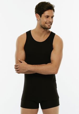 Top nero senza maniche realizzato in tessuto morbido, con scollatura tonda, abbinato a pantaloni corti aderenti coordinati.