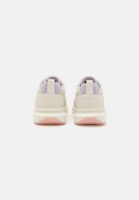 Sneakers beige con morbidi accenti lavanda, caratterizzati da una parte superiore in mesh testurizzato, colli imbottiti e una suola bianca chunky con base rosa.