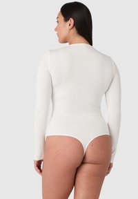 Vit långärmad bodysuit med en åtsittande design, slät textur och en tanga-bakdel, som visar upp en minimalistisk stil utan mönster eller dekorationer.