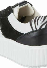 Baskets en cuir noir et suède avec des accents blancs et à rayures zèbre. Elles présentent une épaisse semelle compensée blanche et des matériaux texturés.