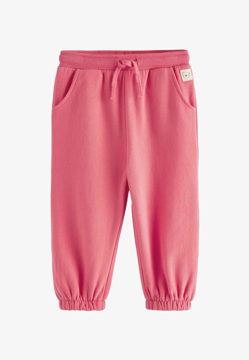 Pink cotton jogger pants with elastic waistband and cuffs, featuring two side pockets and a small label on the waistband. Soft texture.