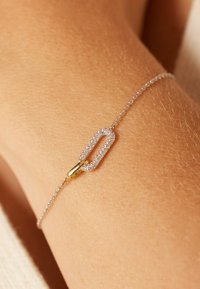 Zilveren kettingarmband met een diamantverstevigde, langwerpige schakelontwerp en een gouden accent, rustend op een pols.