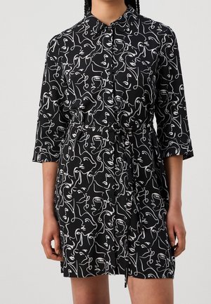 Robe noire avec imprimés abstraits de visages blancs, devant boutonné, col à revers, manches trois quarts et ceinture à nouer amovible à la taille.