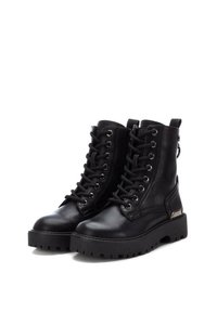 Botas de combate negras con cordones, hechas de cuero, con una suela de plataforma gruesa, costuras reforzadas y detalles metálicos en el tacón.