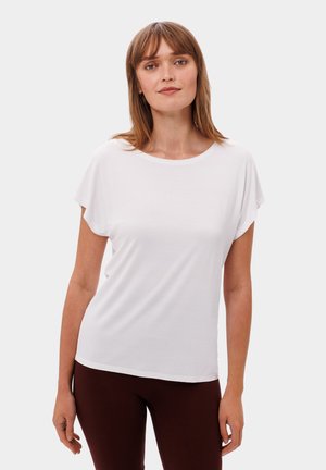 Witte T-shirt met korte mouwen en een ronde halslijn, met een gladde textuur en een relaxte pasvorm, gecombineerd met bruine leggings.