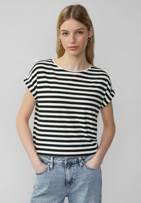 Schwarz-weiß gestreifes T-Shirt mit kurzen Ärmeln und rundem Halsausschnitt, aus weichem Stoff. Kombiniert mit hellblauen Jeans.