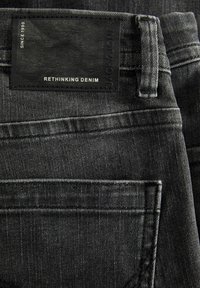 Tumedate hallide teksased, millel on nahkmeetri silt "JACK & JONES" ja "RETHINKING DENIM" reljeefiga. Puhta lõikega ja standardsete taskutega.