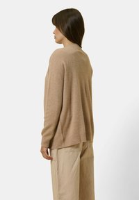 Ljusbrun, oversized tröja tillverkad av ett mjukt material. Har en rund halslinning, ribbad nederkant och sänkta axlar. Matchas med beige byxor.