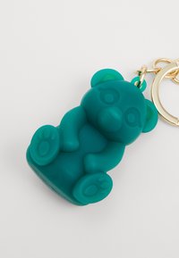 Teal silicone bear keychain with a glossy finish, rounded shape, and paw details. Features a gold metal ring for attachment.