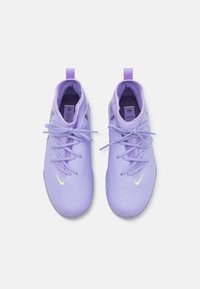Zapatillas deportivas moradas en un material sintético suave con cordones y un logo de Nike en verde lima. Cuentan con una punta redondeada y un acolchado en el cuello.