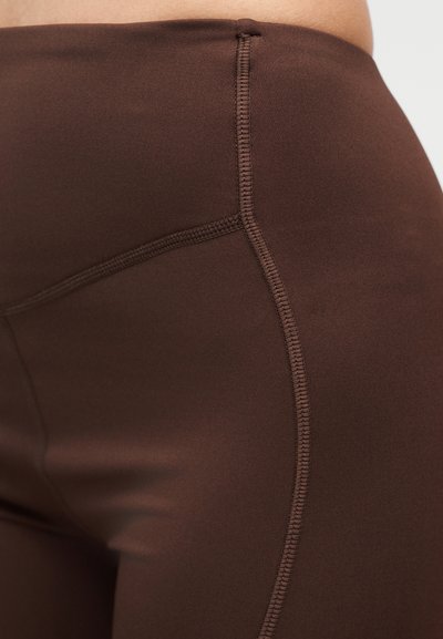 Leggings marrones hechos de material liso y elástico, con costuras planas y una cintura alta para mayor comodidad y flexibilidad.