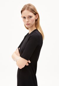 Schwarzes, geripptes Kleid mit rundem Ausschnitt und kurzen Ärmeln, figurbetonter Silhouette, glatter Textur und knielangem Design.