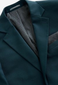 Mörkgrön texturerad kavaj med ett mönstrat svart foder och ficknäsduk. Har skarpa slag och en elegant design för formella tillfällen.