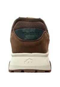 Zapatilla sintética marrón con parte superior de malla, suela de goma y media suela blanca. Presenta un logo en el talón y acentos texturizados.