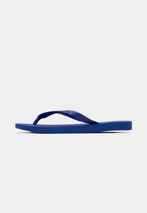 Tongs bleues en caoutchouc avec une sangle texturée et une semelle plate, présentant un design minimaliste sans marque visible.