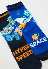Blaue und schwarze Socken mit Weltraum-Themenmotiven. Eine Seite zeigt einen Raumroboter, die andere Seite hat den Text "HYPERSPEED" und "SPACE" in Orange und Weiß.