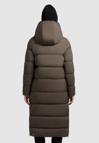 Gewatteerde, lange bruine jas met een kap, voorzien van horizontale secties, een gladde textuur en een ritsdetail aan de zoom. Zwart gebreide beanie hierboven weergegeven.