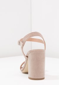 Nude sandały na obcasie o teksturowanym zamszowym wykończeniu, otwartym z tyłu, cienkich paskach oraz masywnym obcasie dla stabilności. Klasyczny design z minimalistycznymi akcentami.