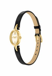 Esfera de reloj ovalada en tono dorado con marcadores mínimos, correa de cuero negra texturizada, hebilla dorada y logo de Tory Burch debajo de la posición de las 12 en punto.