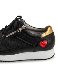 Schwarze Ledersneaker mit einem goldenen Akzent an der Ferse, einem seitlichen Reißverschluss und einem roten, mit Pailletten verzierten Herzdetail. Die Sohle ist weiß.