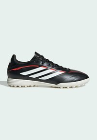 Chaussure de football Adidas Copa noire avec des bandes blanches, des accents rouges, et une semelle en caoutchouc cloutée blanche, vue de profil.
