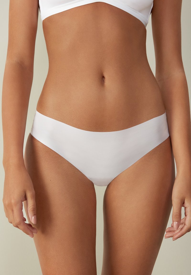 Weiße Stretch-Bikini-Höschen mit glatter Textur und minimalistischer Gestaltung, die einen niedrigen Schnitt und einen breiten elastischen Bund aufweisen.