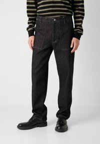 Pantaloni din denim negri cu croială dreaptă, având două buzunare frontale, închidere cu nasture superior și detalii subtile de cusătură galbenă.