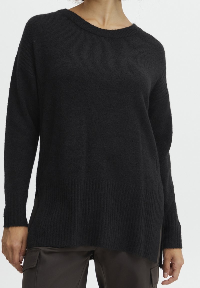 Czarny sweter dzianinowy o luźnym kroju, z ribbowanym dołem i długimi rękawami. Miękka tekstura i szeroki dekolt dodają mu wyjątkowego charakteru.