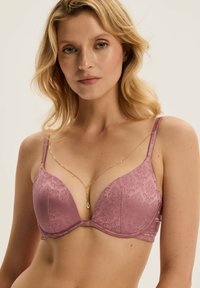 Fioletowy stanik z wyściółką, z teksturowanym wzorem kwiatowym i regulowanymi ramiączkami, z delikatnym złotym łańcuszkiem jako akcentem przy dekolcie.