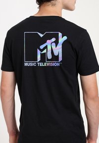 Sort t-shirt med et holografisk MTV-logo og tekst på ryggen. Lavet af bomuld med rund hals og korte ærmer.
