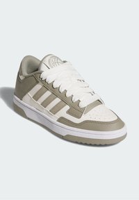 Adidas-sneakers med överdel i vitt läder och detaljer i olivgrön, strukturerad sula och vävda snören. Lufthål i tån för ventilation.
