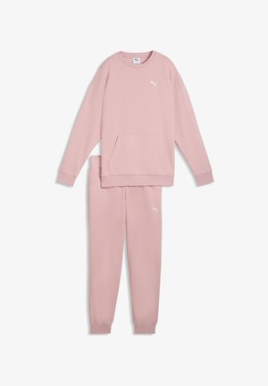 Felpa rosa chiaro e pantaloni della tuta abbinati realizzati in materiale morbido. Presentano una tasca frontale e dettagli con logo bianco su entrambi gli articoli.