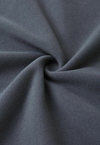 Miękka, teksturowana szara tkanina o gładkiej powierzchni, z widocznym wzorem spirali utworzonym przez fałdy. Idealna do zastosowań odzieżowych lub jako tapicerka.