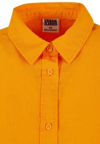 Bright orange, short-sleeved collared shirt with a button-down front and two matching buttons. Fabric appears textured and lightweight.