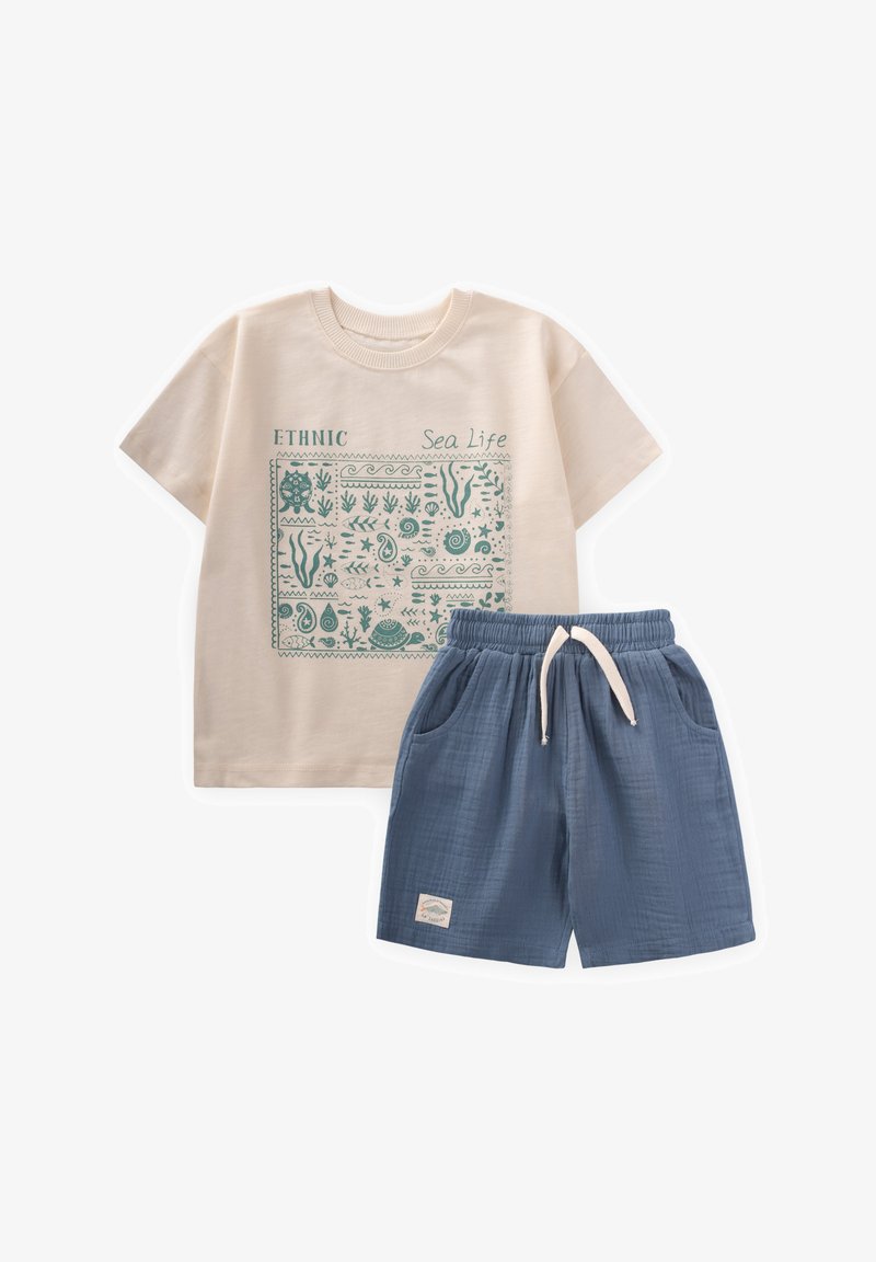 Lühikeste varrukatega kreemivärvi T-särk, millel on tehalise mereelustiku graafika; see on kombineeritud siniste tekstureeritud lühikeste püksidega, millel on elastne vöökoht ja küljetaskud.