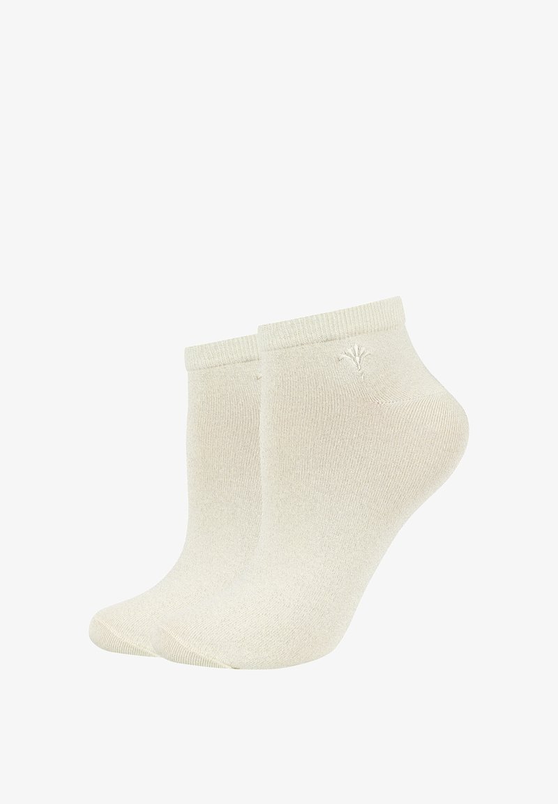Coppia di calzini beige alla caviglia con bordi a coste e un piccolo logo ricamato vicino alla parte superiore su sfondo bianco.
