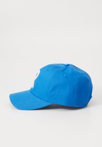Blue baseball cap made of cotton with a curved brim, featuring a white letter "P" on the front and a button detail on the top.
