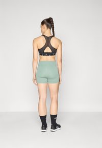 Mustmust mustreiningiga disainiga must spordibra ja võtmeaugu detail, koos helesiniste lühikestega. Omab logo rõhutusi ja tekstuuriga kangast.