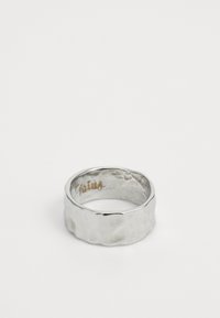 Bred, sølv ring med hammeret tekstur og glatte kanter. Innvendig har den en subtil gravering. Den reflekterende overflaten fremhever detaljene.